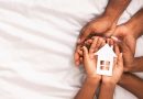 Black family of three holding paper house figure in hands