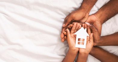 Black family of three holding paper house figure in hands