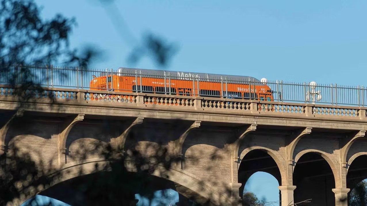 A train passing above ground, as seen from the sidewalk