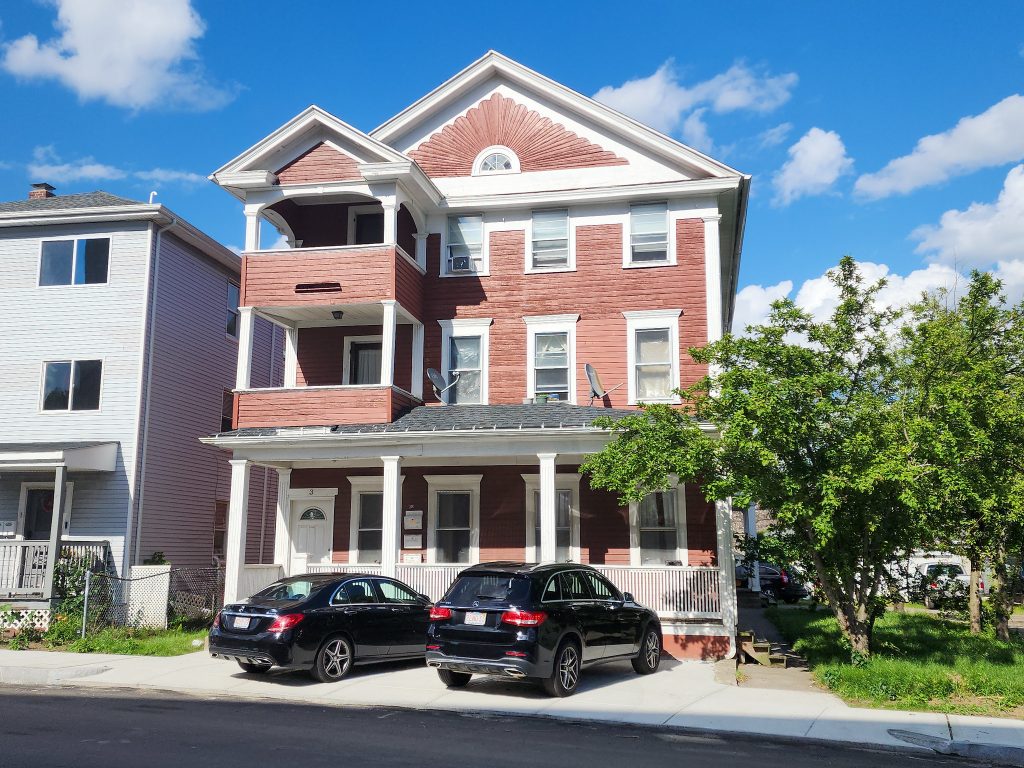 Street view of a New England triple decker house.