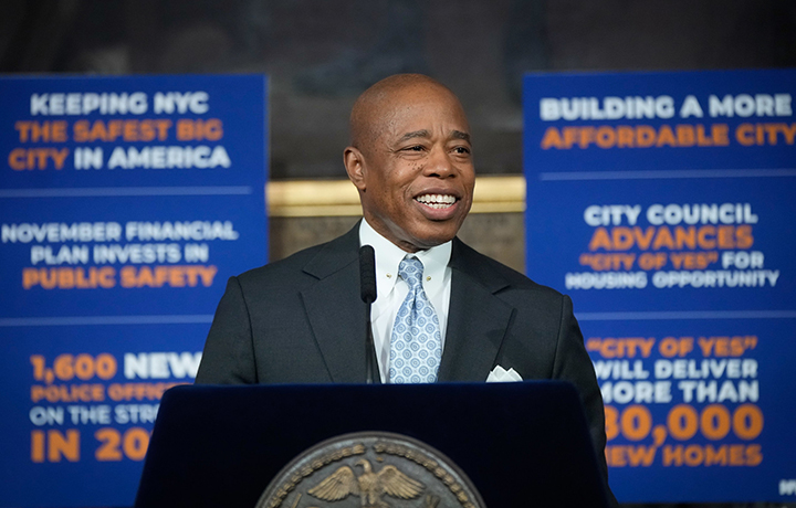 Eric Adams speaking in front of signs celebrating the City of Yes initiative.