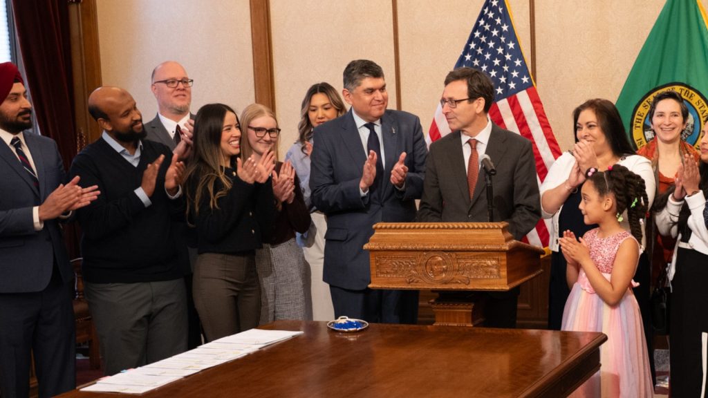Governor Bob Ferguson standing in front of a podium after singing Bills into Laws.