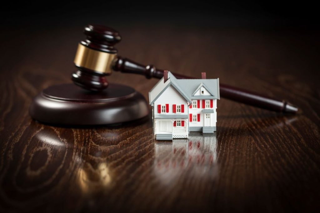A miniature house placed next to a legal gavel.