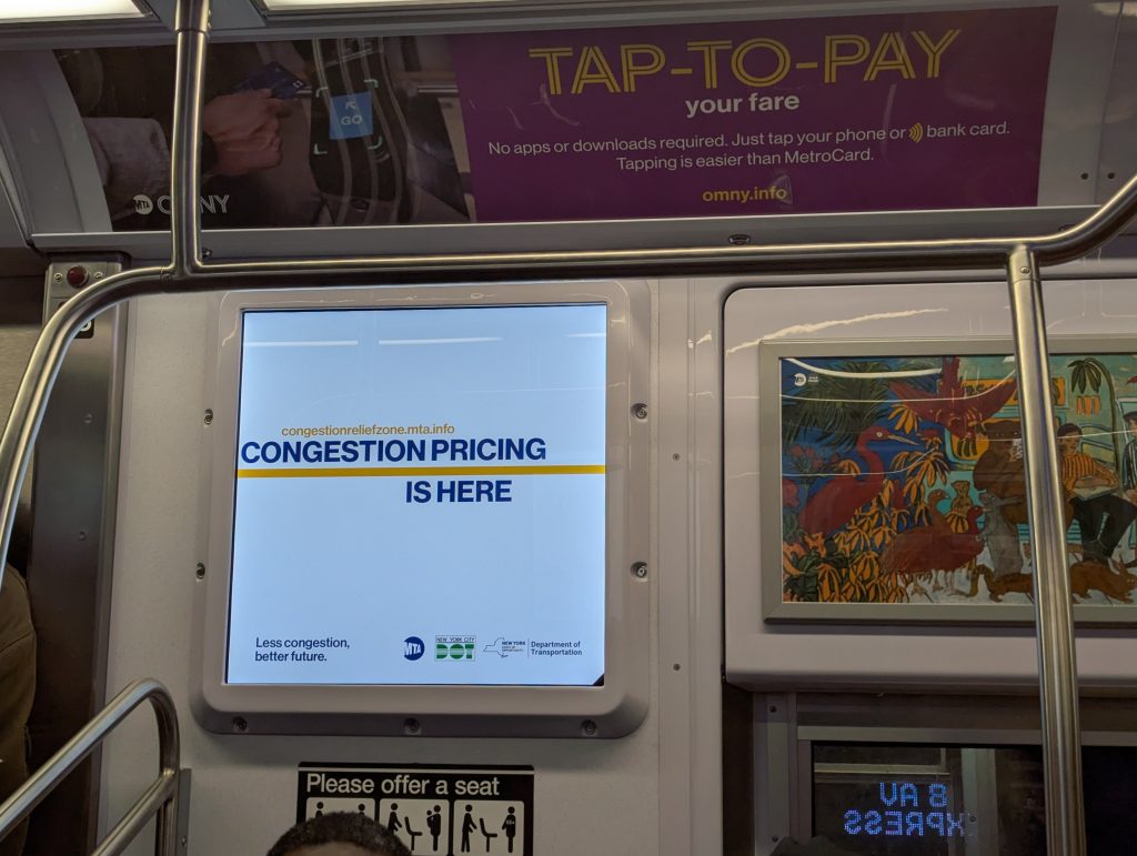 A digital sign announcing the start of congestion pricing in a Subway train.