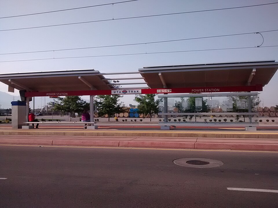 Power Station on the TRAX Green Line from the street with someone sitting on a bench waiting for the train.
