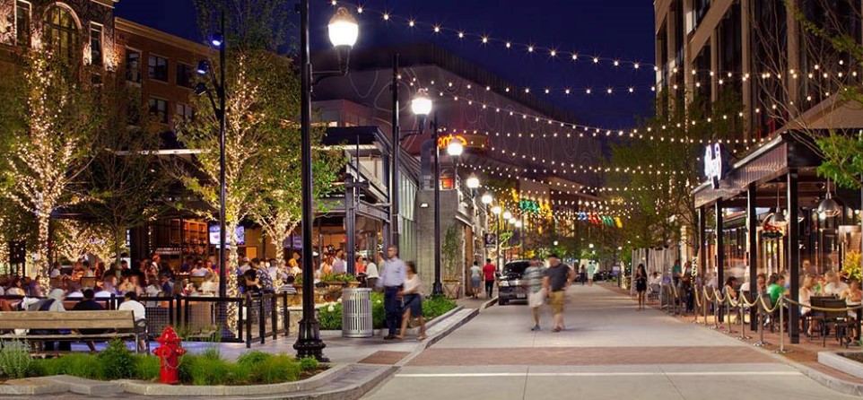 A busy downtown with outdoor seating, a pedestrian walkway, and shops.