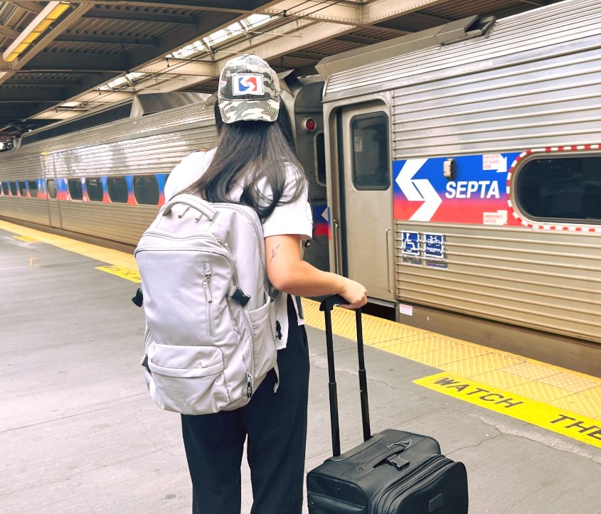 A SEPTA rider boarding a train while holding a suitcase.