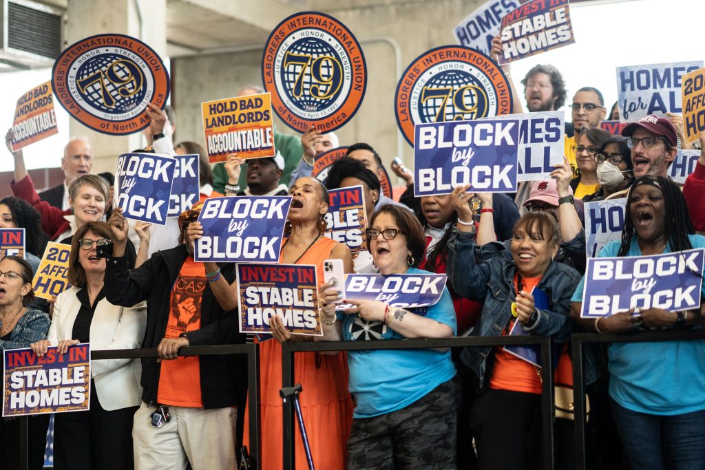 Supporters during Mayor Mamdani’s announcement of “Block by Block: The Housing Plan for a New Era”. They are holding signs that say "Block by Block" and "Invest in Stable Homes."
