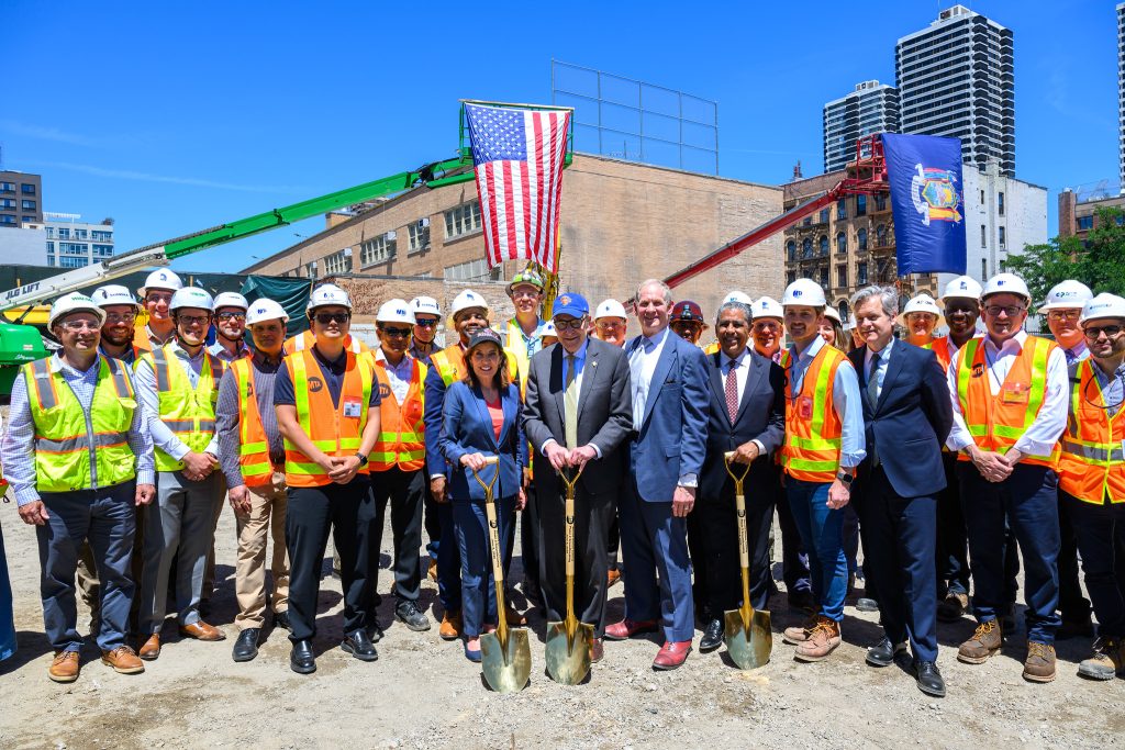 Governor Hochul and MTA officials celebrate the groundbreaking. They are holding shovels and wearing reflective construction gear.