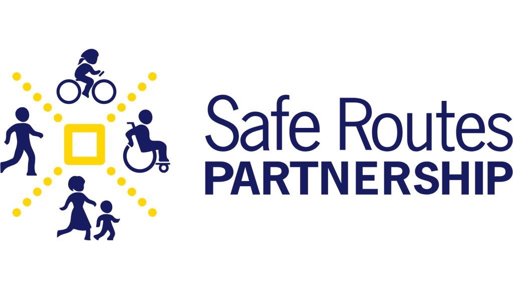 A logo with yellow dotted lines creating four sections. Each section has an illustration in dark blue; clockwise from top: a bicyclist, a wheelchair user, an adult and child walking, and a pedestrian. To the right, the text reads "Safe Routes Partnership."