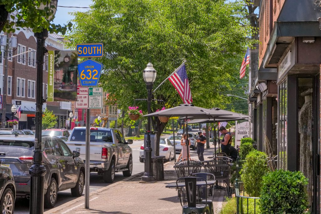 The main street of Cranford with shops and pedestrians.