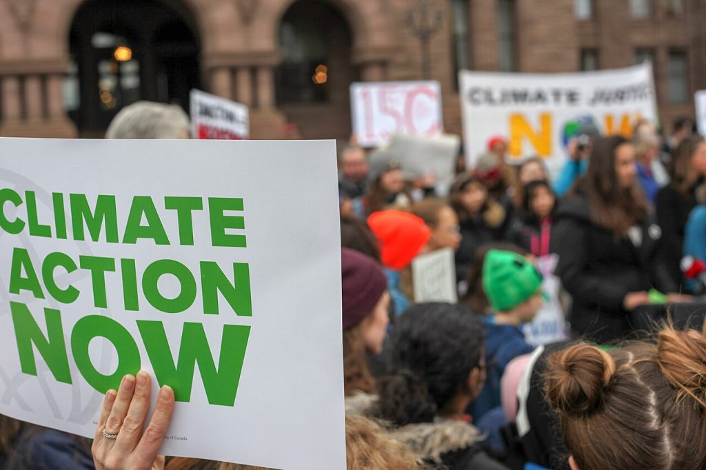 Protester holding a sign that says "Climate Action Now."