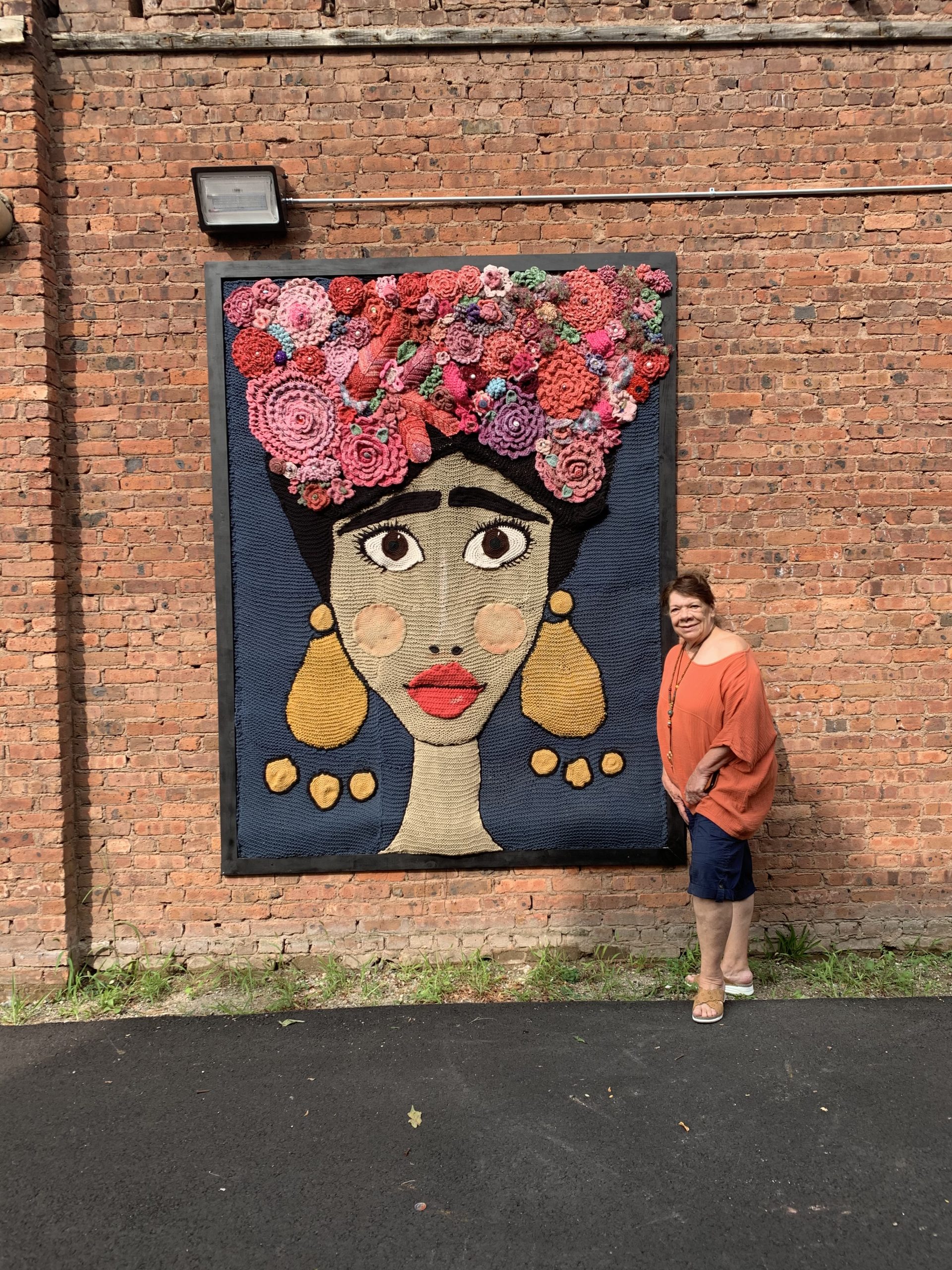 Yarn artist Linda Grant poses with one of her creations in Paseo Alleyway, where the City of Rahway added additional outdoor seating. Image credit: The RA+BP